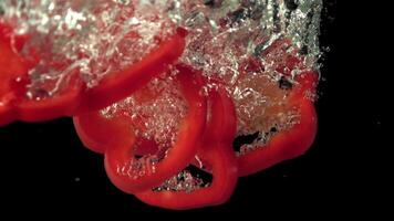 Super slow motion slices of sweet pepper fall under the water. On a black background. Filmed on a high-speed camera at 1000 fps. video