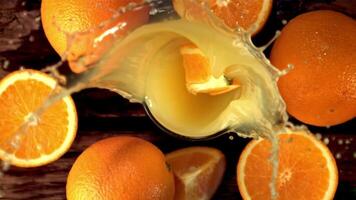 súper lento movimiento pedazo de naranja caídas dentro naranja jugo con salpicaduras filmado a 1000 fps.on un de madera antecedentes. video
