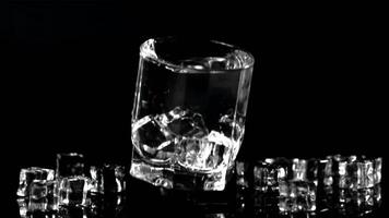 Super slow motion glass with water and ice falls on the table with splashes. On a black background. Filmed on a high-speed camera at 1000 fps. video