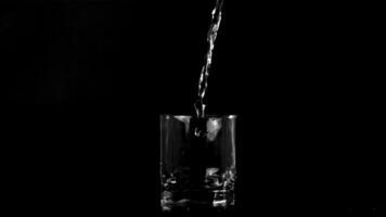 Super slow motion jet of water pours into the glass on the table. On a black background. Filmed on a high-speed camera at 1000 fps. video