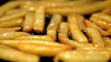 super lento movimento di patatine fritte è fritte nel un' frittura padella con bolle di olio. girato a 1000 fps.on un' nero sfondo. video