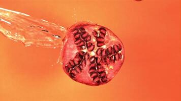 Super slow motion on the slice of the pomegranate pours a jet of water. On an orange background. Filmed on a high-speed camera at 1000 fps. High quality FullHD footage video