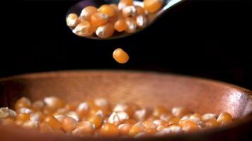 Super slow motion popcorn grains fall from spoon to plate. On a black background. Filmed on a high-speed camera at 1000 fps. High quality FullHD footage video