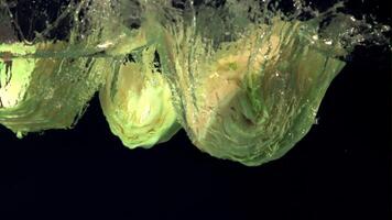 Super slow motion pieces of cabbage fall under the water with air bubbles. Filmed at 1000 fps.On a black background. video