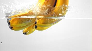 Super slow motion under the water fall bananas on a white background. Filmed on a high-speed camera at 1000 fps. High quality FullHD footage video