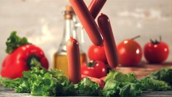 Super slow motion sausages fall on the lettuce leaves on the table. On a gray background.Filmed on a high-speed camera at 1000 fps. High quality FullHD footage video