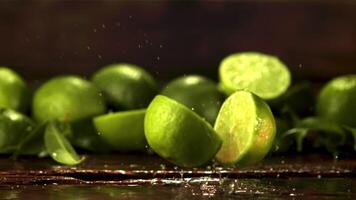 Super slow motion fresh lime falls on the table and splits in two. Against a dark background. Filmed at 1000 fps. video