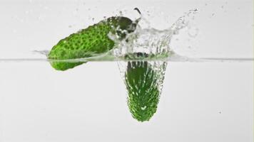 Super slow motion cucumbers fall into water with splashes. On a white background. Filmed on a high-speed camera at 1000 fps. High quality FullHD footage video