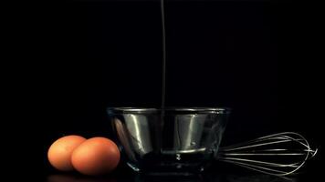 Super slow motion raw egg falls into the bowl with splashes. On a black background. Filmed on a high-speed camera at 1000 fps. video