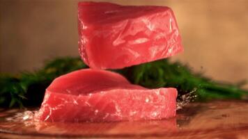 Super slow motion raw tuna steak falls on a cutting board with dill. On a brown background. Filmed on a high-speed camera at 1000 fps. video