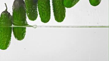 Super slow motion cucumbers fall into water with splashes. On a white background. Filmed on a high-speed camera at 1000 fps. High quality FullHD footage video