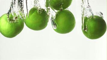 Super slow motion whole green apples fall under the water with air bubbles. On a white background. Filmed on a high-speed camera at 1000 fps. High quality FullHD footage video