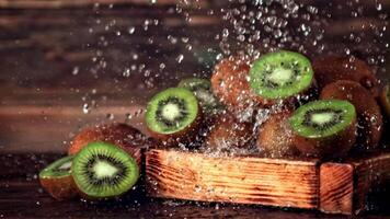 super langzaam beweging Aan de kiwi in de houten dienblad vallen druppels van water. Aan een houten achtergrond. gefilmd Aan een hoge snelheid camera Bij 1000 fps. hoog kwaliteit full HD beeldmateriaal video