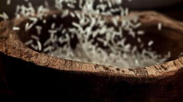 arroz é derramado para dentro uma de madeira tigela. filmado em uma alta velocidade Câmera às 1000 fps. Alto qualidade fullhd cenas video