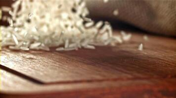 Körner von Reis fallen auf zu ein hölzern Schneiden Tafel. gefilmt auf ein schnelle Geschwindigkeit Kamera beim 1000 fps. hoch Qualität fullhd Aufnahmen video