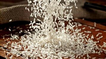 Körner von Reis fallen auf zu ein hölzern Schneiden Tafel. gefilmt auf ein schnelle Geschwindigkeit Kamera beim 1000 fps. hoch Qualität fullhd Aufnahmen video