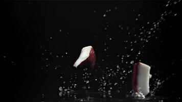 Pieces of coconut fall on the table. On a black background. Filmed on a high-speed camera at 1000 fps. High quality FullHD footage video