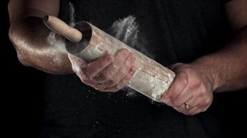 Chef with a rolling pin in his hands and flying flour. Filmed on a high-speed camera at 1000 fps. High quality FullHD footage video