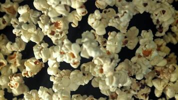 Popcorn flies up and falls down. On a black background. Filmed on a high-speed camera at 1000 fps. High quality FullHD footage video