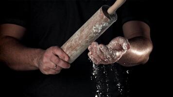 Chef with a rolling pin in his hands and flying flour. Filmed on a high-speed camera at 1000 fps. High quality FullHD footage video