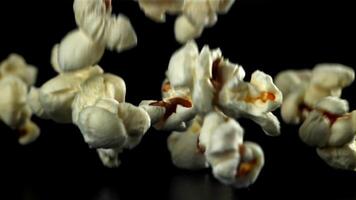 popcorn valt Aan de tafel. Aan een zwart achtergrond. gefilmd Aan een hoge snelheid camera Bij 1000 fps. hoog kwaliteit full HD beeldmateriaal video