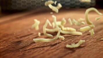 The grated cheese falls on a wooden board. Filmed on a high-speed camera at 1000 fps. High quality FullHD footage video