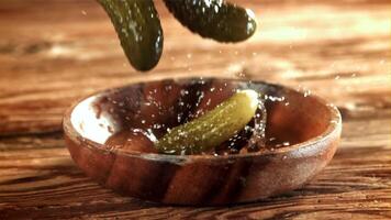 Pickled cucumbers fall into a wooden bowl. Filmed on a high-speed camera at 1000 fps. High quality FullHD footage video