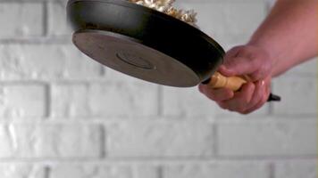 Super slow motion the man's hand with a frying pan tosses popcorn. On a white background. Filmed on a high-speed camera at 1000 fps. High quality FullHD footage video