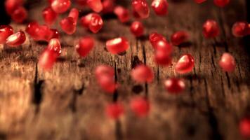 Super slow motion of pomegranate grains roll over the wooden table. On a wooden background.Filmed on a high-speed camera at 1000 fps. High quality FullHD footage video