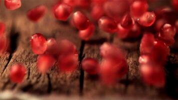Super slow motion of pomegranate grains roll over the wooden table. On a wooden background.Filmed on a high-speed camera at 1000 fps. High quality FullHD footage video