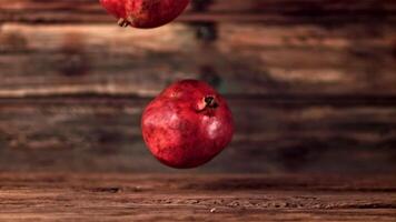 Super slow motion pomegranates fall on a wooden table. On a wooden background.Filmed on a high-speed camera at 1000 fps. High quality FullHD footage video