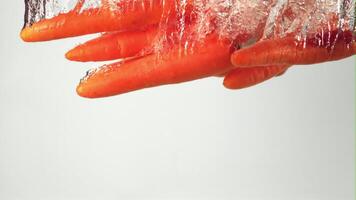 Super slow motion carrot falls under water with air bubbles. On a white background. Filmed on a high-speed camera at 1000 fps. High quality FullHD footage video