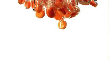 Super slow motion pieces of fresh carrots fall under the water with air bubbles. On a white background. Filmed on a high-speed camera at 1000 fps. High quality FullHD footage video