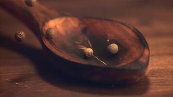 Super slow motion on a wooden spoon fall peas of black pepper. On a wooden background.Filmed on a high-speed camera at 1000 fps. High quality FullHD footage video