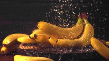 Super schleppend Bewegung Wasser Stürze auf Bananen. auf ein schwarz Hintergrund. gefilmt auf ein schnelle Geschwindigkeit Kamera beim 1000 fps. video