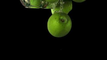 Super slow motion pieces of fresh apple pile fall under the water with air bubbles. On a black background.Filmed on a high-speed camera at 1000 fps. High quality FullHD footage video