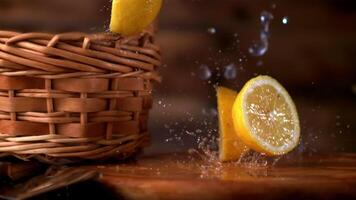 Super slow motion chunks of lemon fall on the table with splashes of water. On a wooden background. Filmed on a high-speed camera at 1000 fps.High quality FullHD footage video