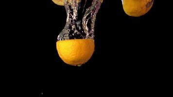 Super slow motion lemon pieces fall under the water with air bubbles. On a black background.Filmed on a high-speed camera at 1000 fps. High quality FullHD footage video