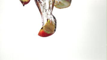 Super slow motion a bunch of apple pieces falls under the water with air bubbles. On a white background. Filmed on a high-speed camera at 1000 fps. High quality FullHD footage video