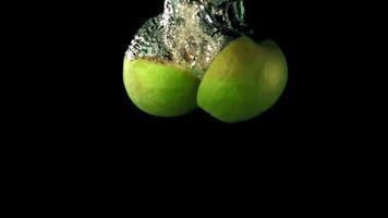 Super slow motion two halves of apple fall under the water with air bubbles. On a black background. Filmed on a high-speed camera at 1000 fps. High quality FullHD footage video