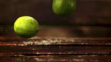 une super lent mouvement pile de Frais citron vert chutes sur le tableau. sur une en bois Contexte. filmé sur une haute vitesse caméra à 1000 ips. video