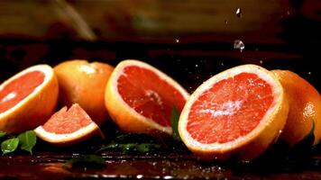 súper lento movimiento en Fresco piezas de pomelo soltar gotas de agua. filmado a 1000 fps.on un de madera antecedentes. video