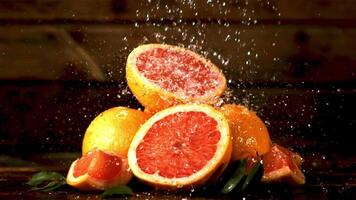 super langzaam beweging Aan vers stukken van grapefruit laten vallen druppels van water. gefilmd Aan een hoge snelheid camera Bij 1000 fps.aan een houten achtergrond. video