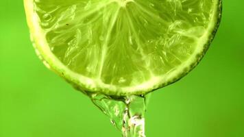 Super slow motion with a round piece of lime pours water.Filmed on a high-speed camera at 1000 fps. On a green background. High quality FullHD footage video