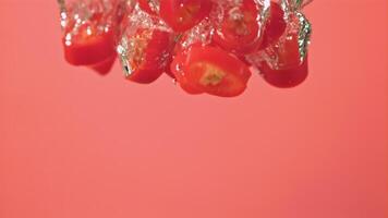 super långsam rörelse bitar av chili paprikor falla under de vatten med luft bubblor. på en rosa bakgrund.filmad på en hög hastighet kamera på 1000 fps. hög kvalitet full HD antal fot video