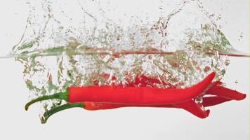 Super slow motion chilli pepper falls into the water with splashes. On a white background.Filmed on a high-speed camera at 1000 fps. High quality FullHD footage video