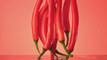 Super slow motion ripe chili pepper falls on the water with splashes. On a pink background. Filmed on a high-speed camera at 1000 fps. High quality FullHD footage video