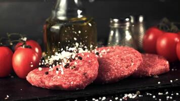 Super slow motion salt and pepper falls on the raw burger. On a black background. Filmed on a high-speed camera at 1000 fps. video