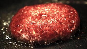 Super slow motion burger patty is fried with bubbles of oil in a frying pan. Filmed at 1000 fps.On a black background. video