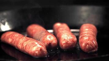 súper lento movimiento crudo salchichas son frito en petróleo en un fritura pan con caliente vapor. filmado en un alta velocidad cámara a 1000 fps.on un negro antecedentes. video